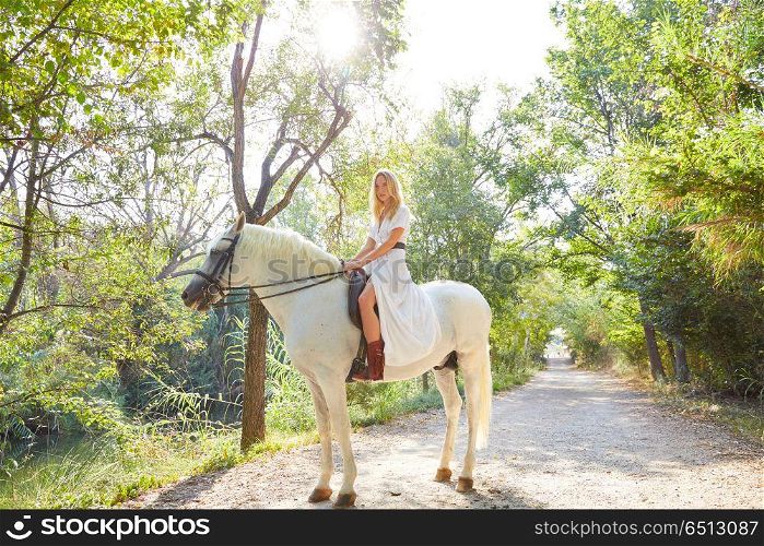 Blond girl woman riding a white horse in track. Blond girl woman riding a white horse in a forest track outdoor