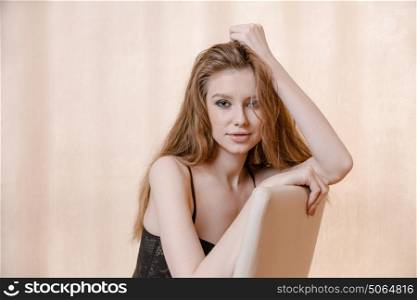 Blond haired woman in pensive state posing on chair with copyspace