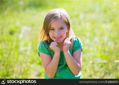 Blond kid girl excited gesture expression in outdoor green meadow