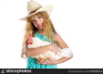 Blond kid girl farmer holding white hen on arms with cowboy hat