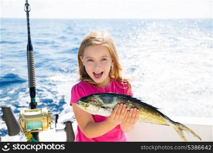 Blond kid girl fishing Dorado Mahi-mahi fish happy with trolling catch on boat deck