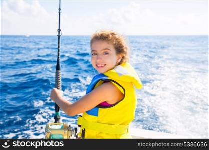 blond kid girl fishing trolling at boat with rod reel and yellow life jacket