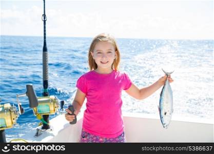 Blond kid girl fishing tuna little tunny happy with trolling catch on boat deck