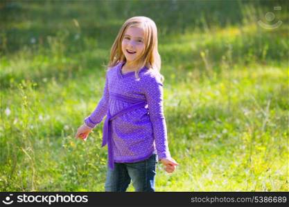 Blond kid girl happy smiling in outdoor green meadow