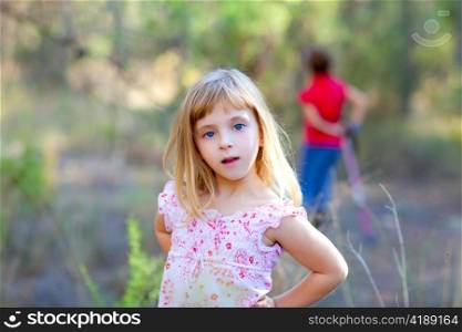 blond kid girl in forest park posing to camera