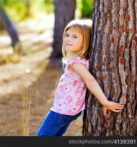 blond kid girl on autumn tree trunk in forest park