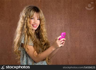 Blond kid girl playing with mobile smartphone portrait on vintage background
