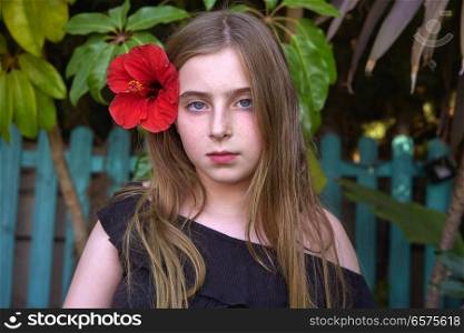 Blond kid girl portrait with red flower in hair at garden