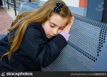 Blond kid girl pretending being sleep on a street bench