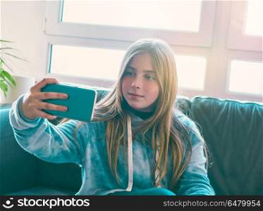 Blond kid girl selfie with a window background. Blond kid girl selfie with a window background at indoor sofa