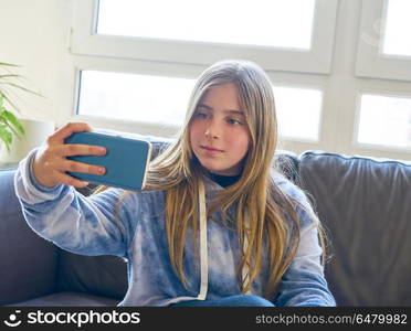 Blond kid girl selfie with a window background. Blond kid girl selfie with a window background at indoor sofa