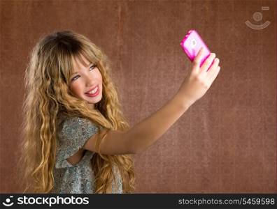 Blond kid girl taking pictures with mobile smartphone portrait on vintage background