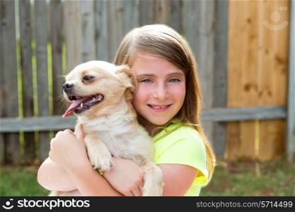 Blond kid girl with chihuahua pet dog playing happy outdoor