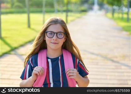 Blond kid student girl with glasses and backpack in the park back to school