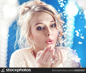 Blond lady blowing pieces of shiny crystal