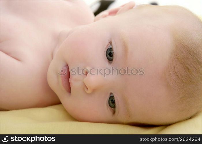 Blond little baby laying on bed portrait horizontal image