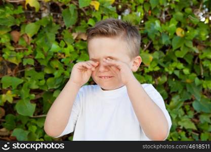 Blond little boy rubbing eyes for allergy