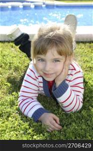 blond little girl laying on pool grass