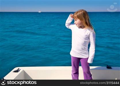 blond little kid girl sailing in a boat looking away at the sea