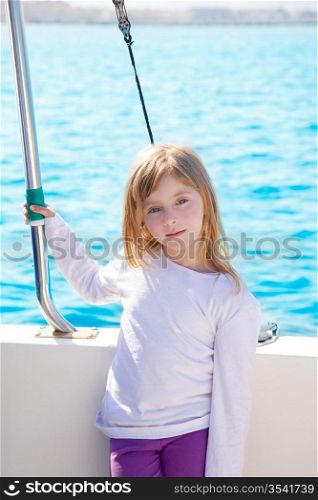 blond little kid girl sailing in a boat smiling at the sea