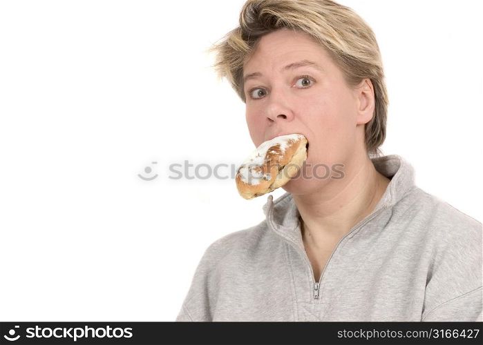 Blond mature woman looking surprised that she is actually eating a bun