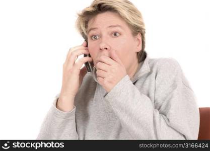 Blond mature woman looking very shocked while on the phone
