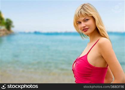 blond nice woman with pink top on the seaside looking in camera