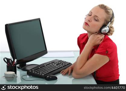 Blond office worker listening to music at desk