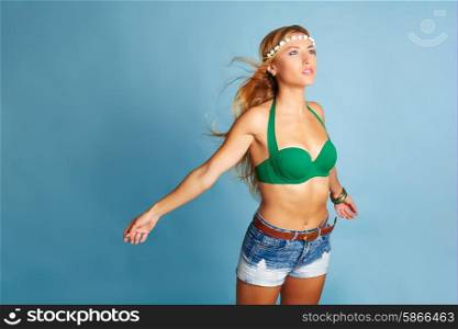 Blond sexy girl with short jeans on blue background and wind in hair