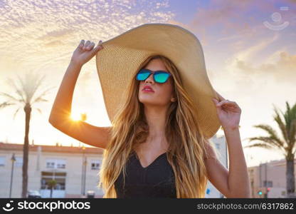 Blond teen girl sunglasses and pamela sun hat at palm tree sunset