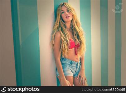 Blond teen summer girl in a blue stripes wall background filtered image