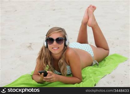 Blond teenager at the beach listening to music