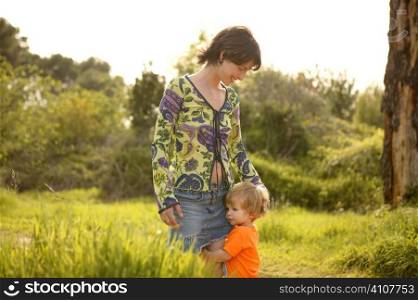 blond toddler son hug his mother in green outdoor