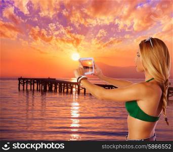 Blond tourist girl taking photos of Mallorca Alcudia beach sunset photomount