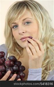 Blond woman about to eat a grape