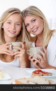 Blond woman and blond girl having breakfast