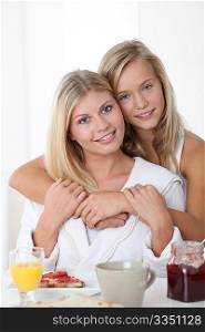 Blond woman and blond girl having breakfast