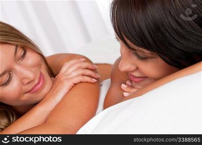 Blond woman and brunette having fun in bed together