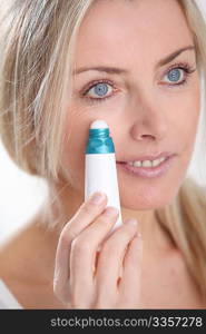Blond woman applying anti-aging serum on her skin