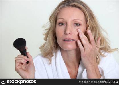 Blond woman applying makeup