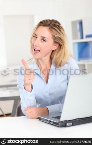 Blond woman at work showing thumb up