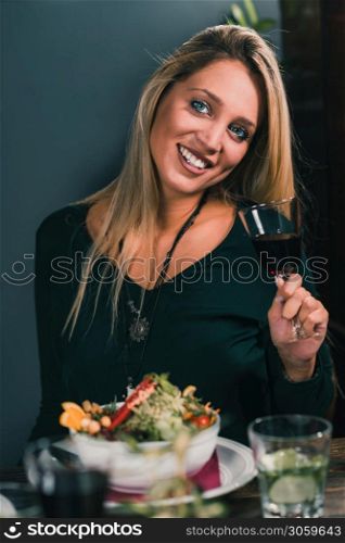 Blond Woman Drinking Red Wine in restaurant