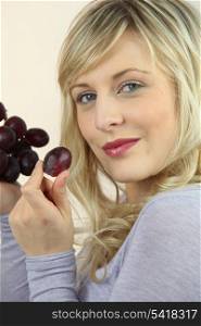 Blond woman eating bunch of grapes