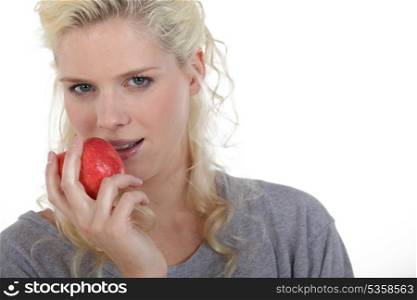 Blond woman eating red apple