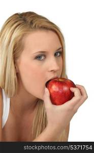 Blond woman eating red apple