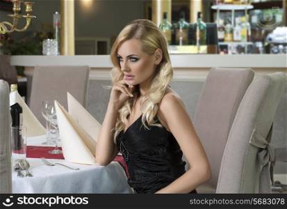 blond woman elegant , with hair style sitting at the restaurant and thinking for somebody she is looking away