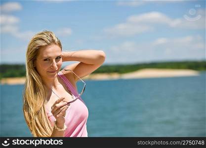 Blond woman enjoy summer sun with sunglasses at sea