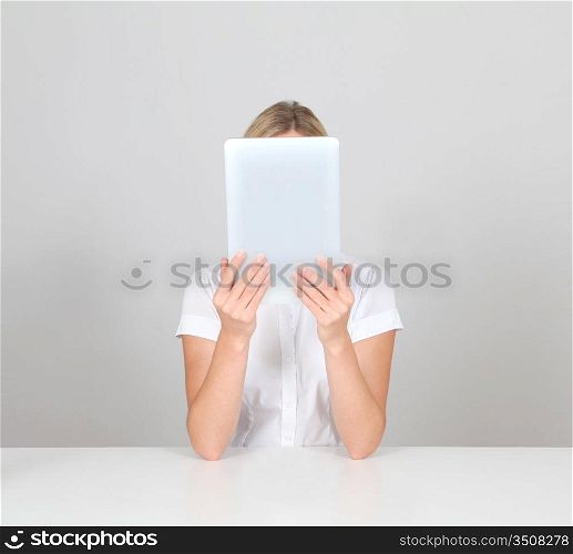 Blond woman hiding face behind electronic tablet
