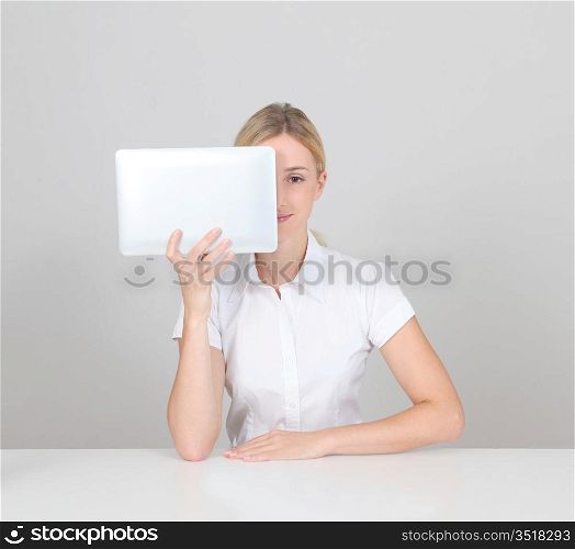 Blond woman hiding face behind electronic tablet