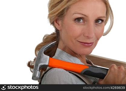 Blond woman holding hammer over shoulder